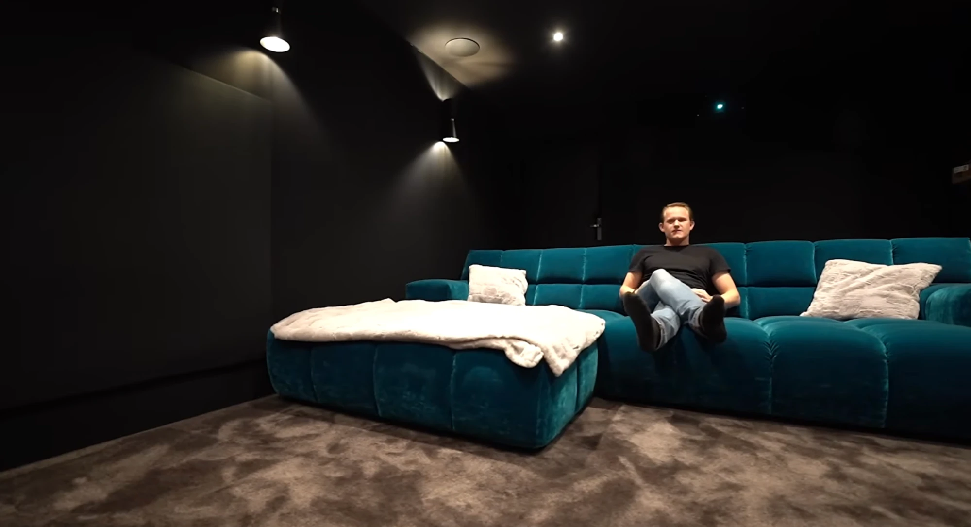 Cinéma privé Chamonix : écran de projection en action, Dolby Atmos 7.2.6 Salle de cinéma privé Chamonix — écran de projection et canapé velours bleu — réalisation AV Concept Products